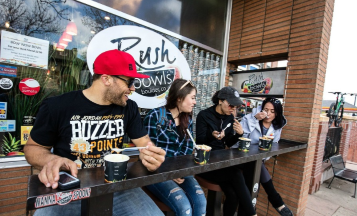 These happy customers enjoy Rush Bowls smoothie bowls outside the restaurant.
