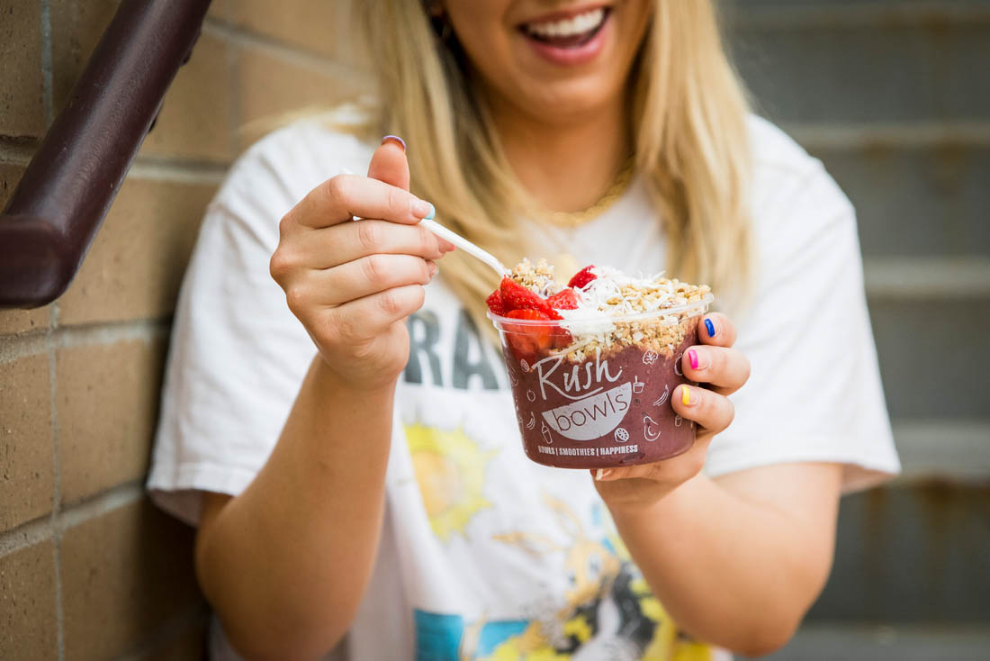 A happy customer with a smoothie bowl from Rush Bowls, a top acai bowl franchise opportunity.